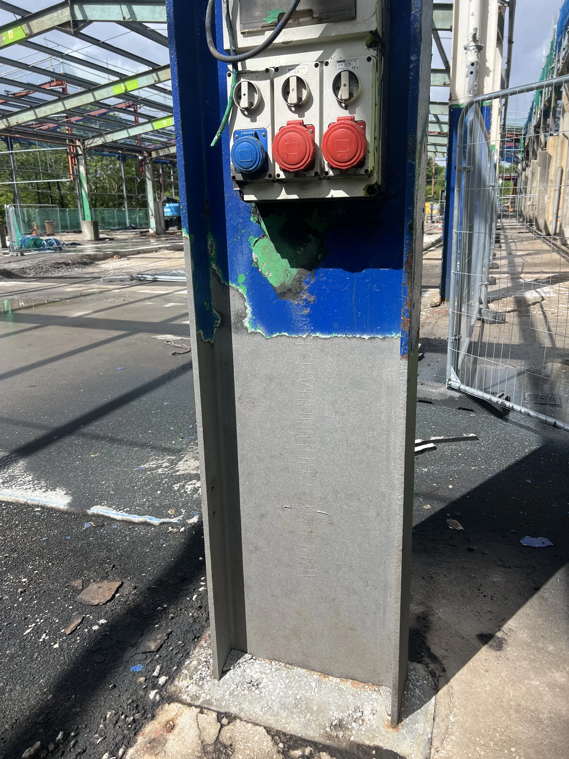 Worker in protective equipment carrying out surface-preparation work on a steel column