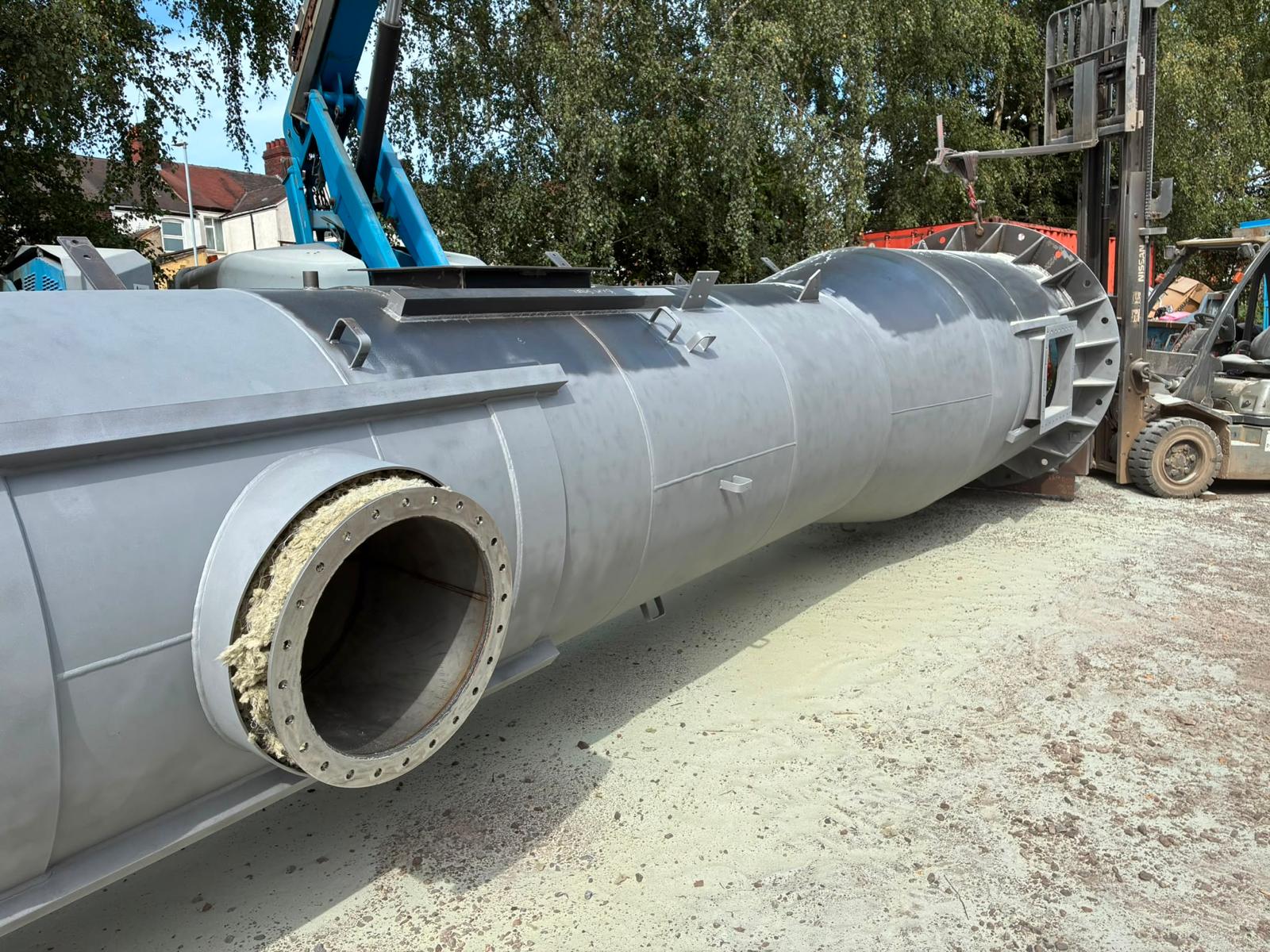 Commercial steel chimney during surface preparation — cylindrical body and fittings