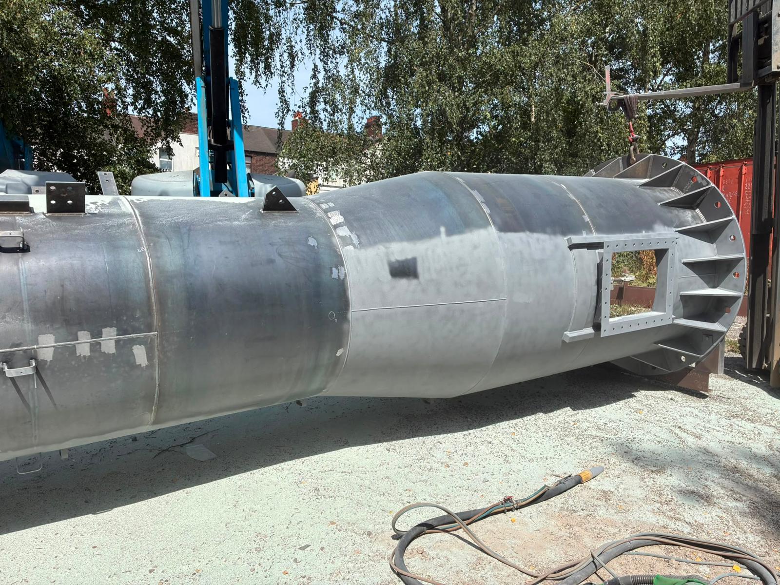 Steel chimney during commercial surface preparation — full assembly view